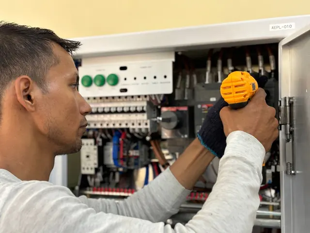 Eletricista com furadeira montando disjuntores em um quadro de distribuição