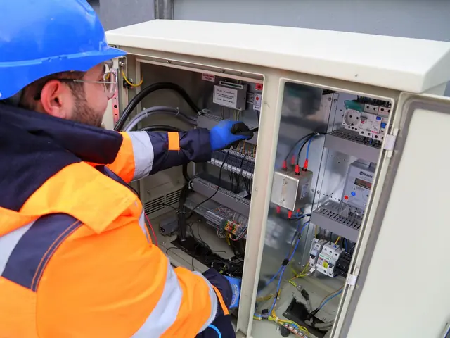 Eletricista de capacete azul e colete laranja conferindo disjuntores em um quadro