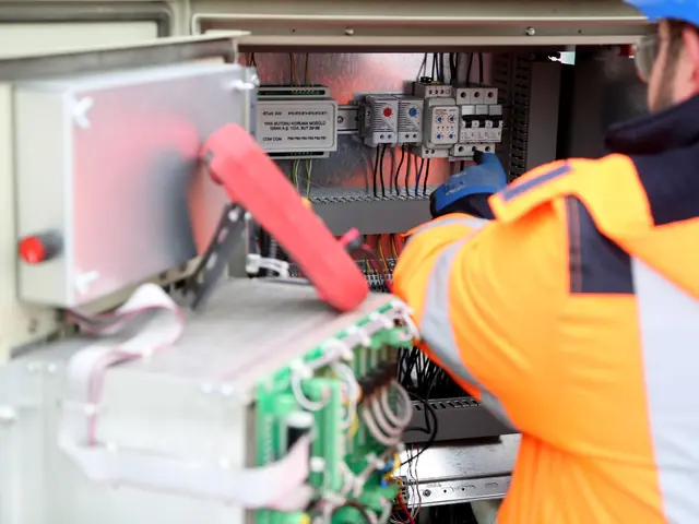 Dois eletricistas de colete laranja trabalhando em um painel elétrico