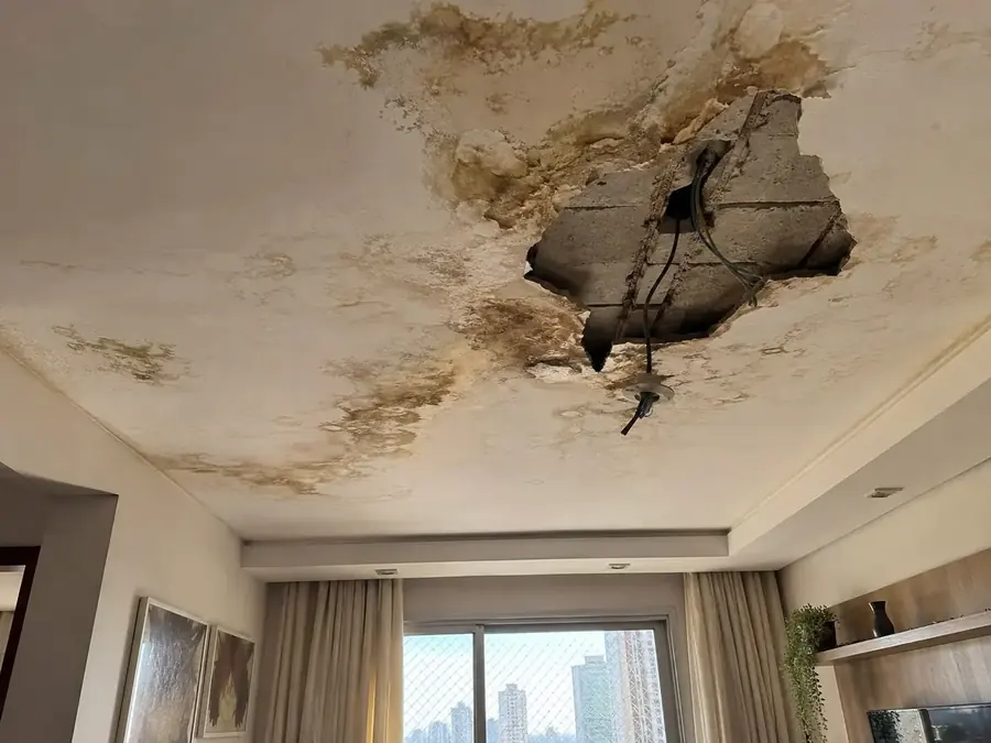 Teto com abertura e manchas de infiltração antes do reparo