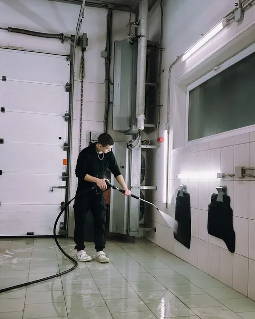 Profissional lavando com jato de água um piso em uma sala clara