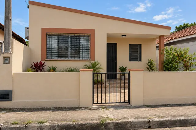 A mesma casa depois da reforma, com reboco novo na cor areia e portão preto